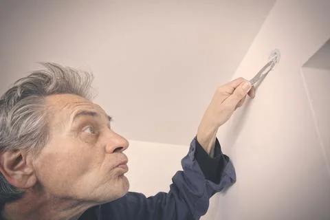 Man working on refresh of walls and ceiling before new painting of apartment Stock Photos