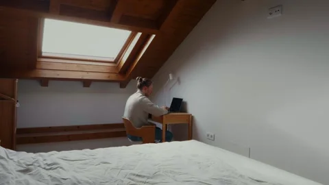 Man working remotely in attic apartment cozy home office lifestyle Video stock 334547369