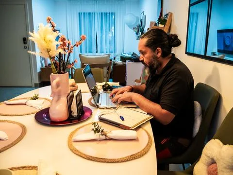 Man Working Remotely at Dining Table 库存照片