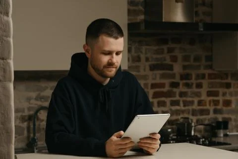 A man working remotely on his tablet. A businessman with a beard working at h 스톡 사진