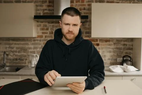A man working remotely on his tablet. A businessman with a beard working at h Stock Photos