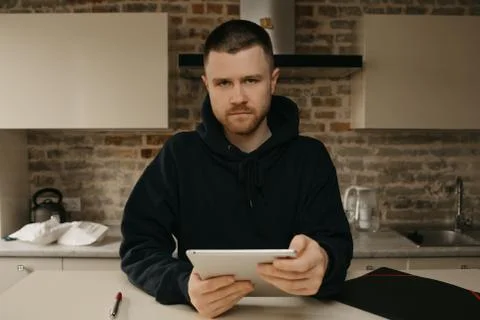 A man working remotely on his tablet. A businessman with a beard working at h Stock Photos