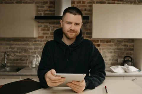 A man working remotely on his tablet. A businessman with a beard working at h Stock Photos