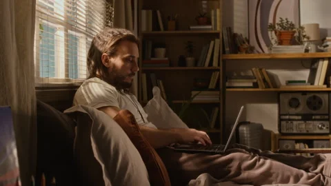 Man Working Remotely on Laptop Computer while Reclining on Bed at Home Stock Footage 337505537