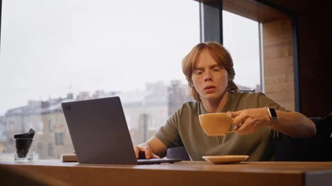 Man Working Remotely on Laptop with Cup of Coffee in Cafe Stock Footage 344365347