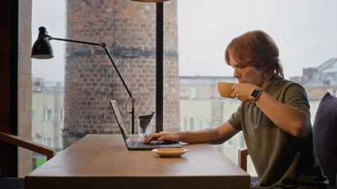 Man Working Remotely on Laptop Drinking Coffee in Cafe Stock Footage 344368739