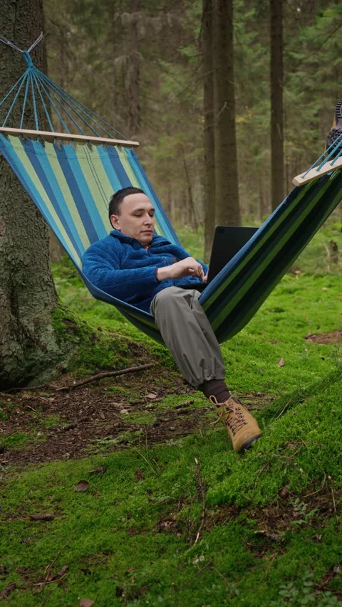 Man Working Remotely on Laptop Lying in Hammock in Forest Stock Footage 348057769