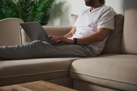 Man Working Remotely on Laptop While Relaxing on a Comfortable Sofa Stock Photos