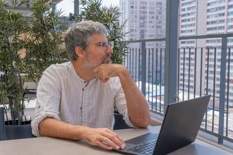 Man working remotely thinking on an urban balcony 스톡 사진