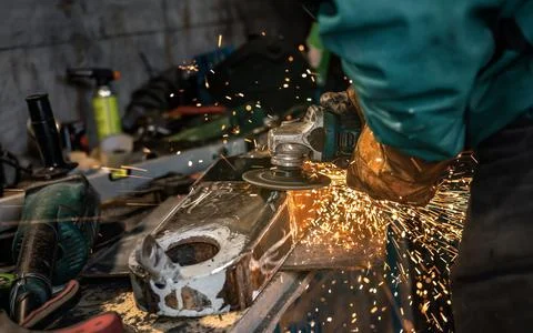 Man working with rotary angle grinder at workshop, closeup detail, orange sparks Stock Photos