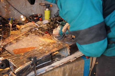 Man working with rotary angle grinder at workshop, closeup detail, orange sparks Stock Photos