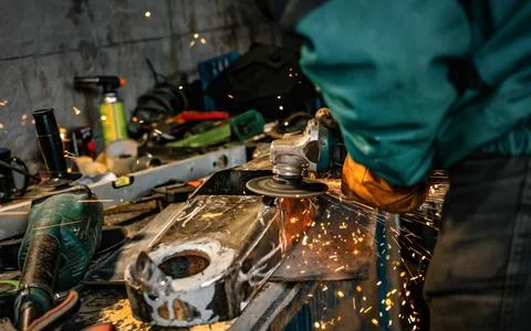 Man working with rotary angle grinder at workshop, closeup detail, orange s.. Stock Photos