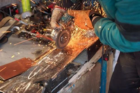 Man working with rotary angle grinder at workshop, closeup detail, orange s.. Foto stock