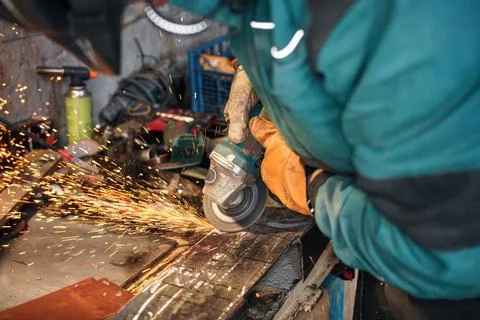 Man working with rotary angle grinder at workshop, closeup detail, orange s.. Stock Photos