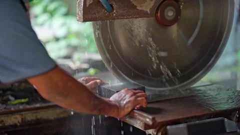 A man is working with a saw on a stone in close-up. A man cuts granite with an Stock Footage 239841263