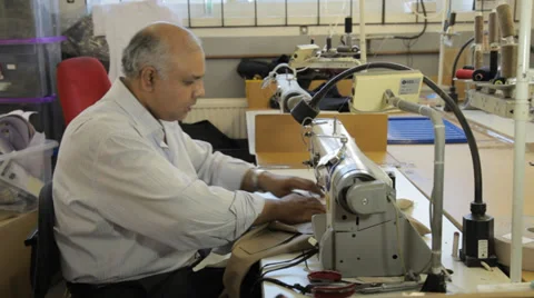 Man working on a sewing machine in a dressmaker's factory Stock Footage 31340869
