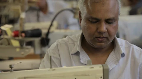 Man working on a sewing machine in a dressmaker's factory Stock Footage 31343565