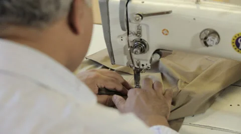 Man working on a sewing machine in a dressmaker's factory (over the shoulder Stock Footage 31361482