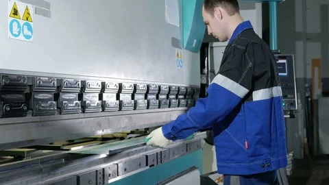 Man working with sheet metal on CNC hydraulic press brake. He puts the part and Stock Footage 71652354