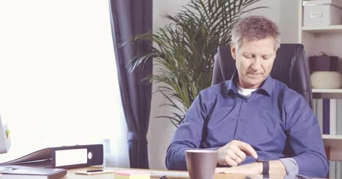Man working with smartwatch at his desk in a home office 스톡 동영상 61135335