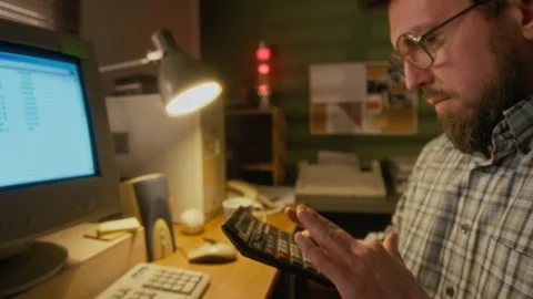 Man Working on Spreadsheet on Retro Computer and Counting on Calculator Stock Footage 327237246