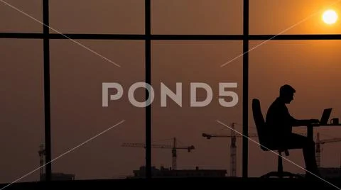 The man working at the table near a window on an industrial city background Stock Photos