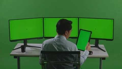 Man Working With Tablet And Multiple Computer Monitor With Mock Up Green Screen Stock Footage 249624997