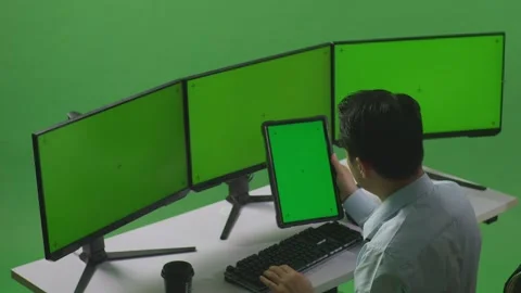 Man Working With Tablet And Multiple Computer Monitor With Mock Up Green Stock Footage 249634272
