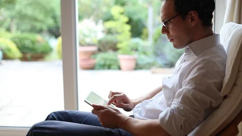 Man working on tablet computer at home and then looking at camera Stock Footage 98093702