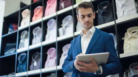Man working on tablet computer at shirt store Stock Footage 82722223