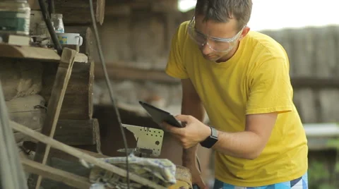 A man working on a tablet, puts aside tablet and begins sawing metal with angule Stock Footage 65000219