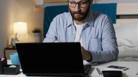 Man working talking on video connection and drinks coffee. Bearded guy sits at Stock Footage 129382074