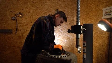 Man working tire mounting, working in garage. Preparing for tire replacement Stock Footage 126505833