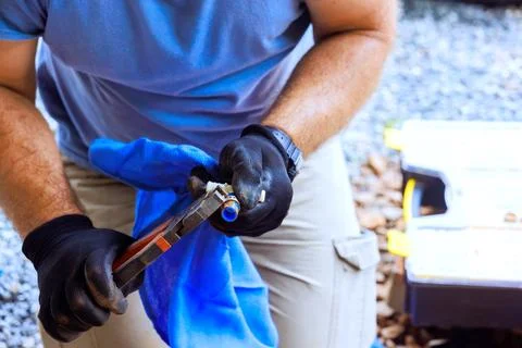 Man working with tools in yard, using gloves, cloth to handle small object Stock Photos
