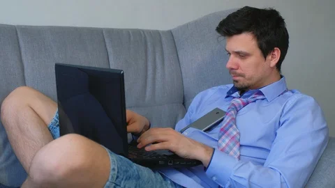 Man working typing on laptop at home sitting on couch, freelance distant work. Stock Footage 128964133