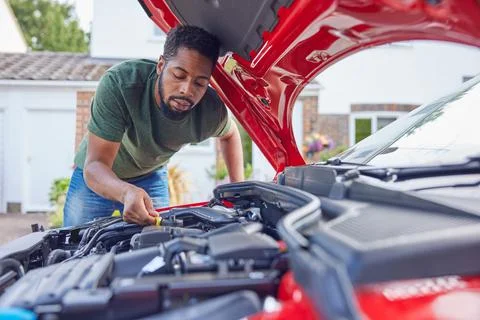 Man Working Under Hood Checking Car Engine Oil Level On Dipstick Stock Photos