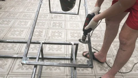 A man in a working uniform and gloves with a drill in his hands 库存影片 145395580