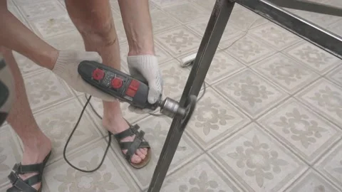 A man in working uniform holds a drill in his hands, which are wearing gloves Vidéo 145182194