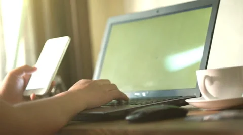 A man is working by using a laptop computer and a smartphone on  wooden table. Stock Footage 60941613