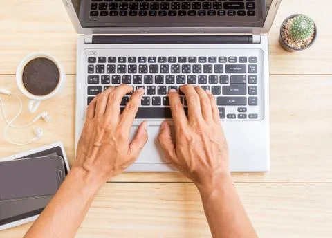 A man is working by using a laptop computer on wooden desk. Foto stock