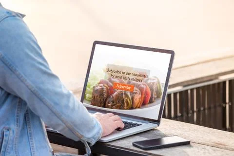 A man is working using laptop doing subscribe for food blog on screen at outdoor Stock Photos