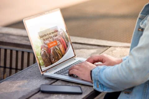 A man is working using laptop doing subscribe for food blog on screen at outdoor Stock Photos