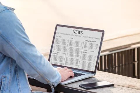 A man is working using laptop reading news article on screen at outdoor Stock Photos