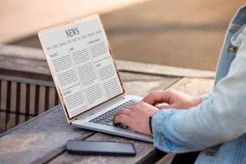 A man is working using laptop reading news article on screen at outdoor Stock Photos
