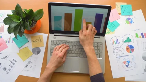 Man working using touchscreen surrounded by a lot of paperwork, hands top view Stock Footage 87977415