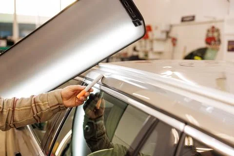 Man working on vehicle in garage, checking potential damage of the car after Stock Photos