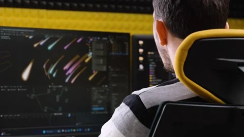 Man working on vibrant motion graphics at dual-monitor editing desk in acoustica Stock Footage 309287697