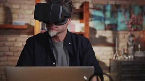Man working with virtual reality googles at home with laptop computer on desk Stock Footage 132204142