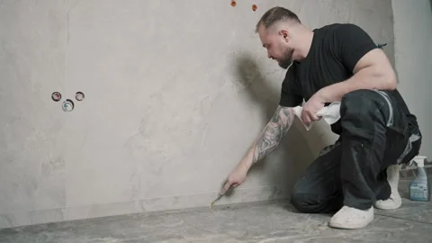 Man working on wall tiling using tools in a bright room Stock Footage 317380969