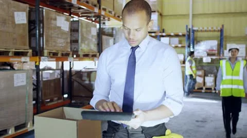 Man working in a warehouse gives instructions to a female worker Stock Footage 13759719